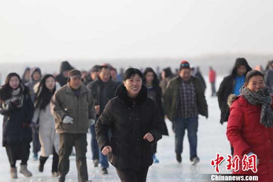 800余名冰上馬拉松競(jìng)賽選手 “全副武裝”前行，他們?cè)谇Ю锉獾牟┧跪v湖面上劃出一條閃亮的軌跡。　年磊 攝